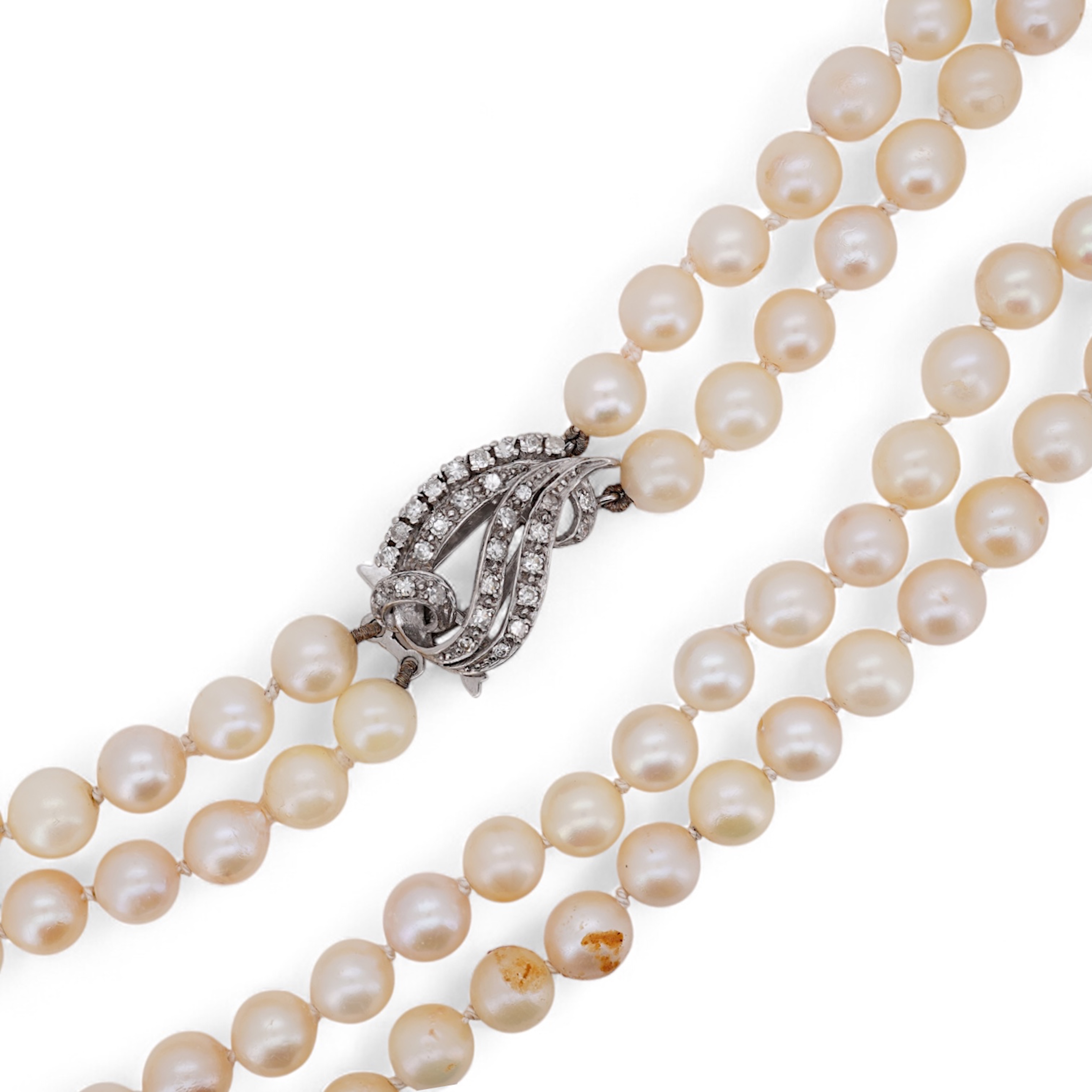 A twin strand cultured pearl necklace with a diamond cluster set white metal scroll shaped clasp, 60cm.